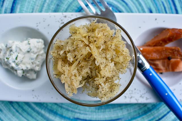 Top view of a Dilly Delight Sauerkraut in a bowl with cream cheese and another sliced dish at the background. | MakeSauerkraut.com