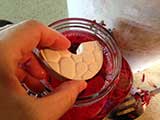 Tamarack Stoneware Fermentation Weights held by the forefinger and thumb finger. | MakeSauerkraut.com