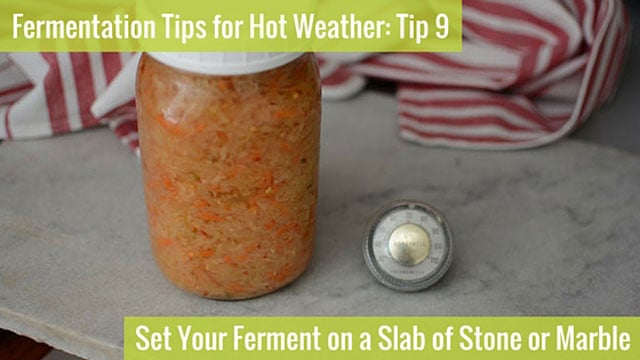 Jar of sauerkraut and small travel thermometer on top of stone slab counter top. | MakeSauerkraut.com