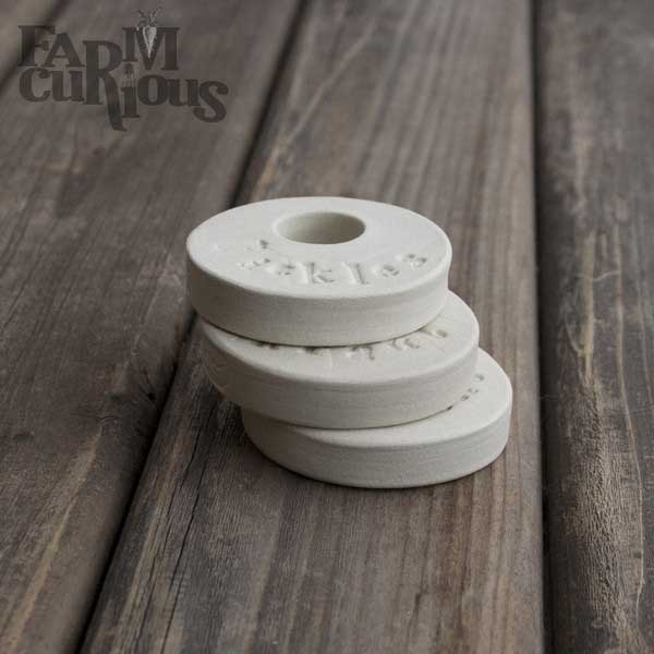 Three stacked white porcelain Farm-Curious fermentation weights. | MakeSauerkraut.com