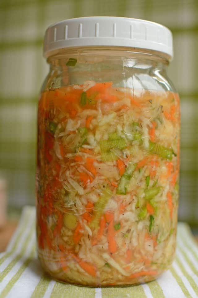 Close-up of a filled jar of sauerkraut over stiped white and green cloth. | MakeSauerkraut.com