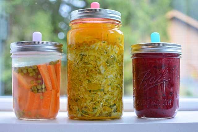 Three jars of different sauerkraut with MasonTops Pickle Pipe & Pickle Pebble. | MakeSauerkraut.com