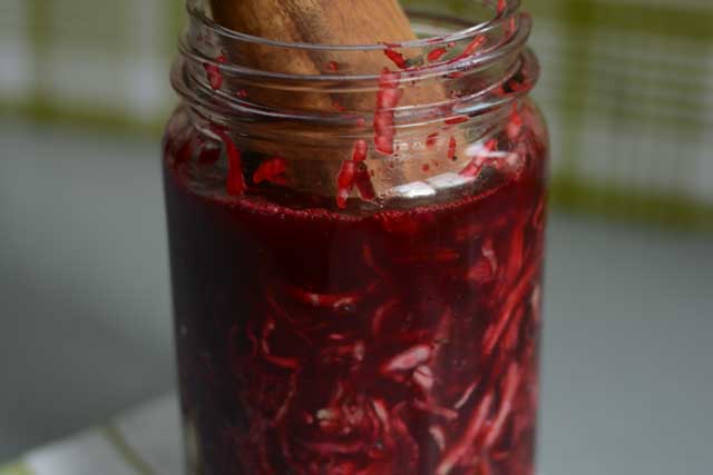 A jar of sauerkraut with a wooden scooper inside. | MakeSauerkraut.com