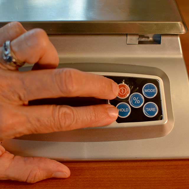 Fingers reaching to press buttons on the MyWeigh KD-8000 digital scale. | MakeSauerkraut.com