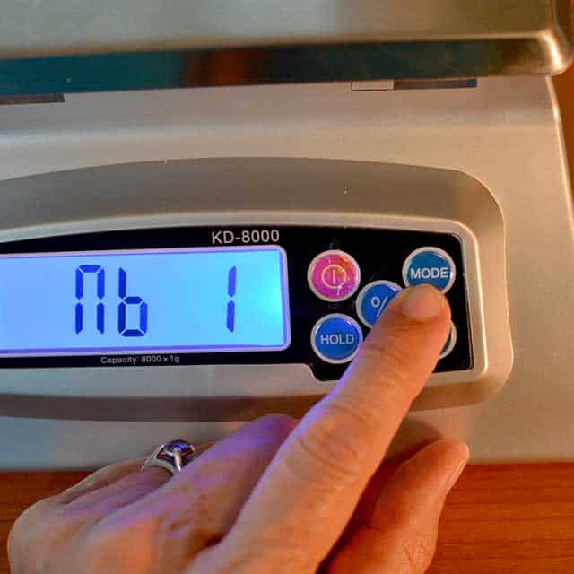 Fingers reaching to press "mode" on the MyWeigh KD-8000 digital scale. | MakeSauerkraut.com