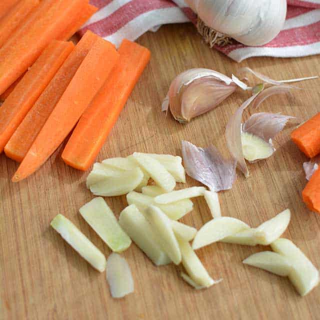 Sliced carrots, sliced garlic cloves and 
 with garlic peelings scattered around. | MakeSauerkraut.com
