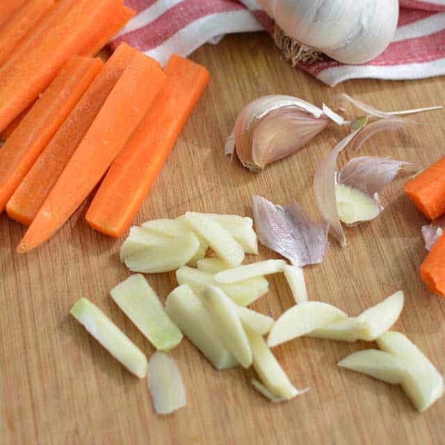 Sliced carrots, sliced garlic cloves and
with garlic peelings scattered around. | MakeSauerkraut.com