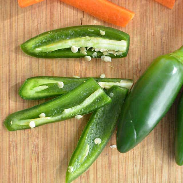 Sliced jalapeno with some seeds sticking to the slices. | MakeSauerkraut.com