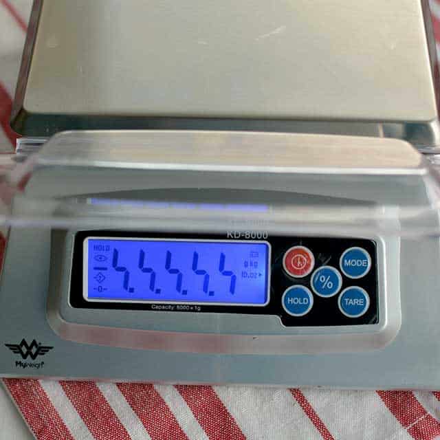 Front view of MyWeigh KD-8000 digital scale on striped red and white cloth and monitor showing "99999". | MakeSauerkraut.com