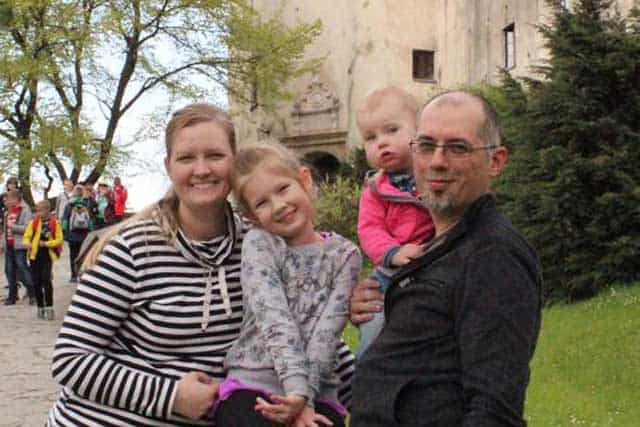 A man holding his daughter and the mother holding the elder daughter while smiling at the camera. | MakeSauerkraut.com