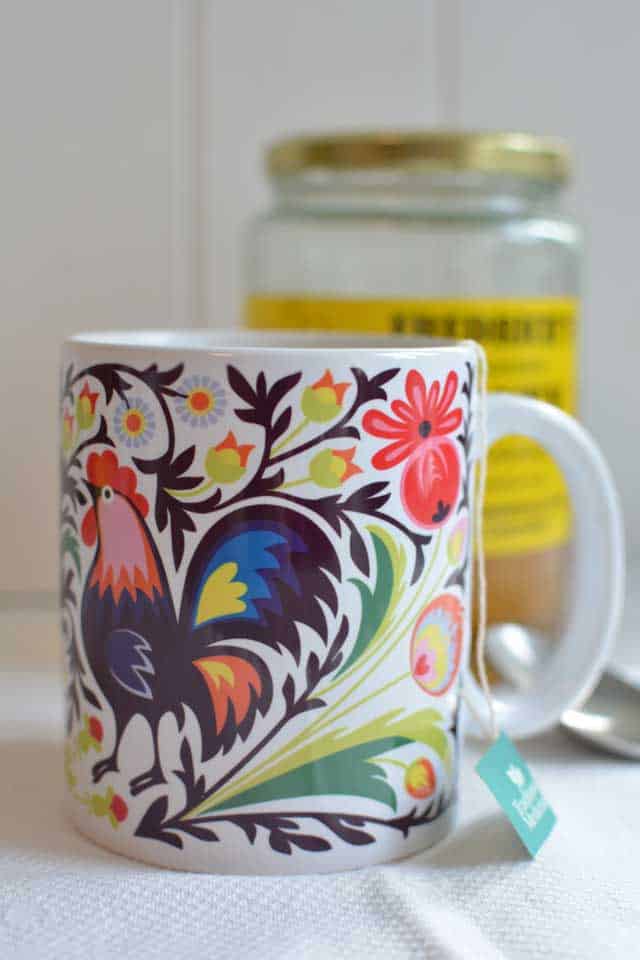 Stone Creek Trading Kaszuby Folk Art Mugs with dominant white finish and colorful rooster design with branches and flower surrounding focal design. | MakeSauerkraut.com
