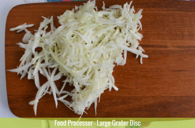 Sliced cabbages on top of a wooden chopping board sliced using the large grater disc of a food processor. | MakeSauerkraut.com