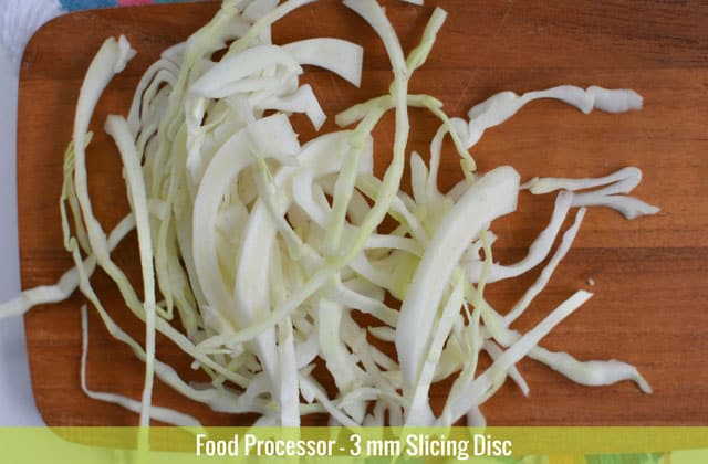 Sliced cabbages on top of a wooden chopping board sliced using the 3mm slicing disc of a food processor. | MakeSauerkraut.com