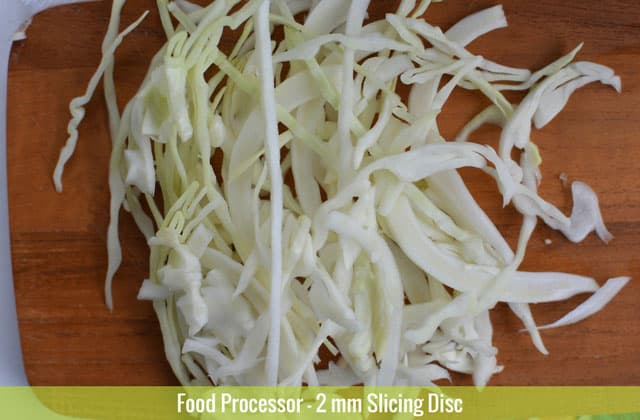 Sliced cabbages on top of a wooden chopping board sliced using the 2mm slicing disc of a food processor. | MakeSauerkraut.com