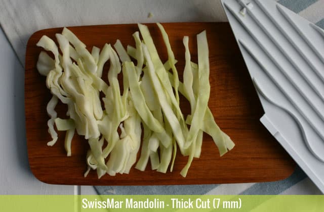 Sliced cabbages in 7 mm thick cut using the SwissMar Mandolin on top of a chopping board and the white panel at the side. | MakeSauerkraut.com