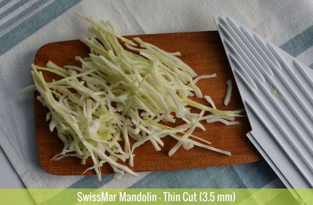 Sliced cabbages in 3.5 mm thin cut using the SwissMar Mandolin on top of a chopping board and the white panel at the side. | MakeSauerkraut.com