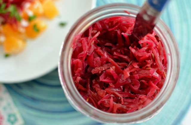 Top of of a glass jar with shredded beets and a fork stabbed in the middle. | MakeSauerkraut.com