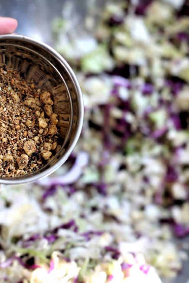 Close-up image of duqqa kraut inside metal bowl with blurred background. | MakeSauerkraut.com