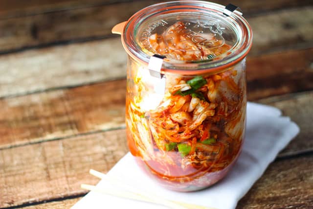 A small jar of kimchi over a white napkin. | MakeSauerkraut.com