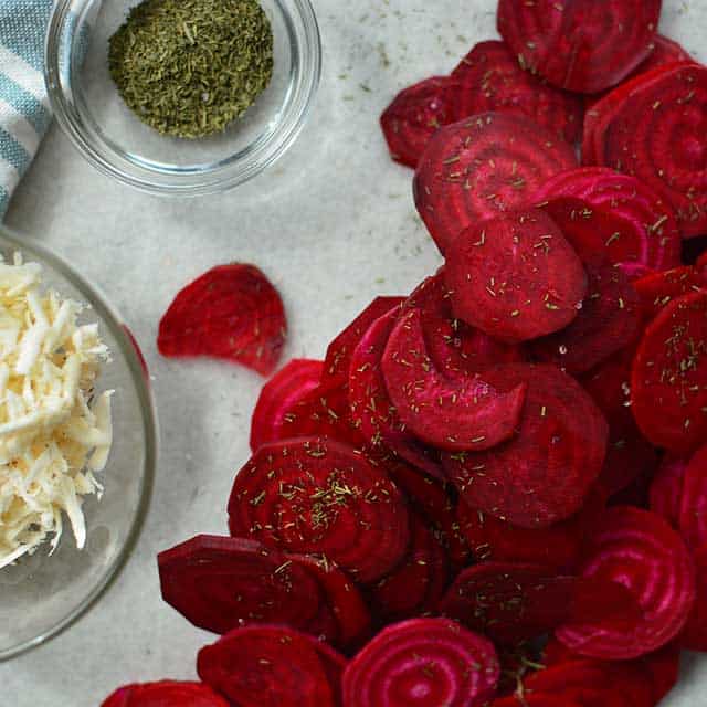 Red fresh beets sliced in circles with some herb seasoning in a small glass bowl and another with glass bowl with white shredded vegetables. | MakeSauerkraut.com
