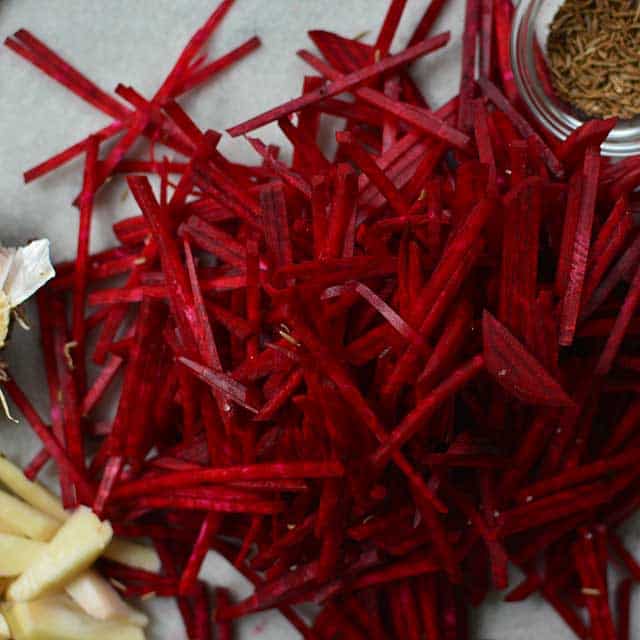 Pile of beetroots in Julienned cut, small glass bowl with herbs.  | MakeSauerkraut.com