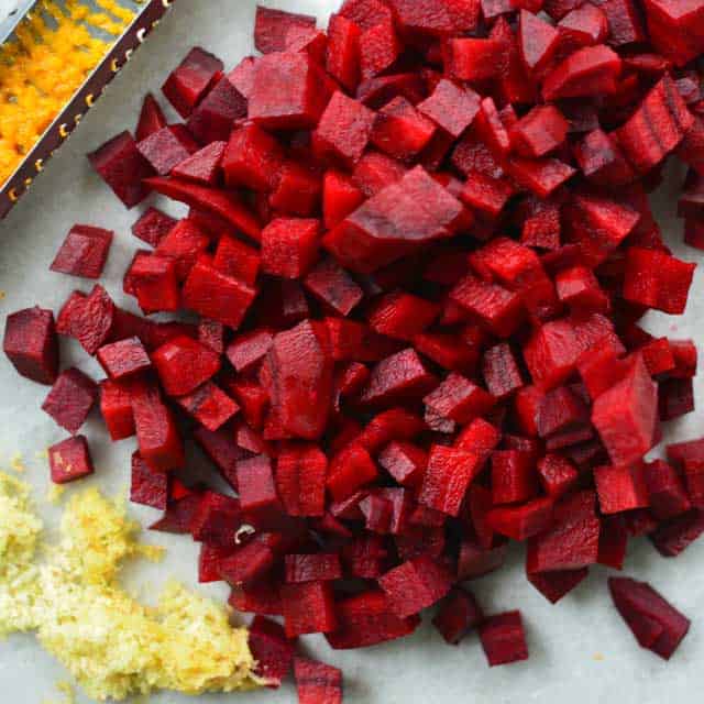 Pile of diced red beets with grated ginger on the bottom left of the picture. | MakeSauerkraut.com