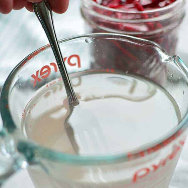 Clear brine inside a measuring container and a fork partially submerged. | MakeSauerkraut.com