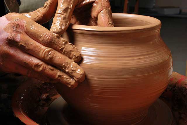 Hands shaping a ceramic clay pot over pottery wheel. | MakeSauerkraut.com