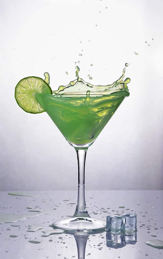 Cocktail glass filed with green liquid and lime at the rim. | MakeSauerkraut.com