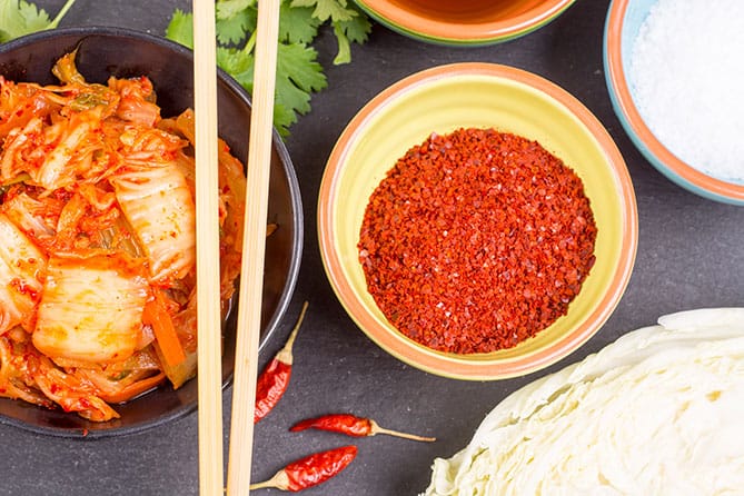 A bowl of Korean chili powder alongside a serving of kimchi. | MakeSauerkraut.com