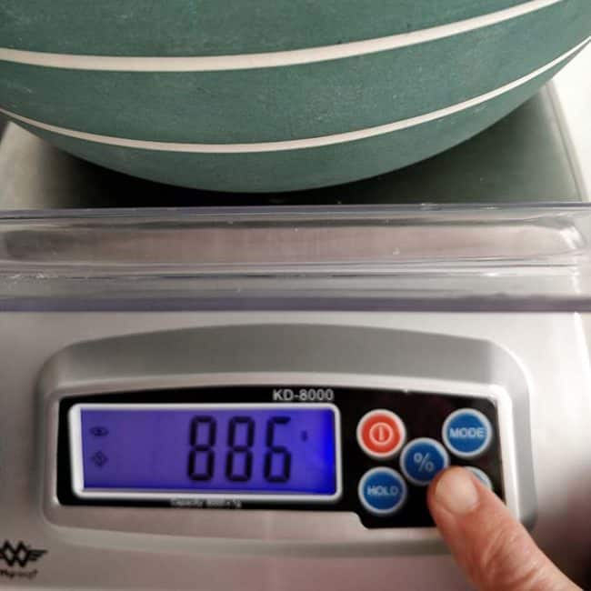 Front view of the MyWeigh KD8000 Digital Scale with the monitor showing "886" and a finger pressing a button in the scale. | MakeSauerkraut.com