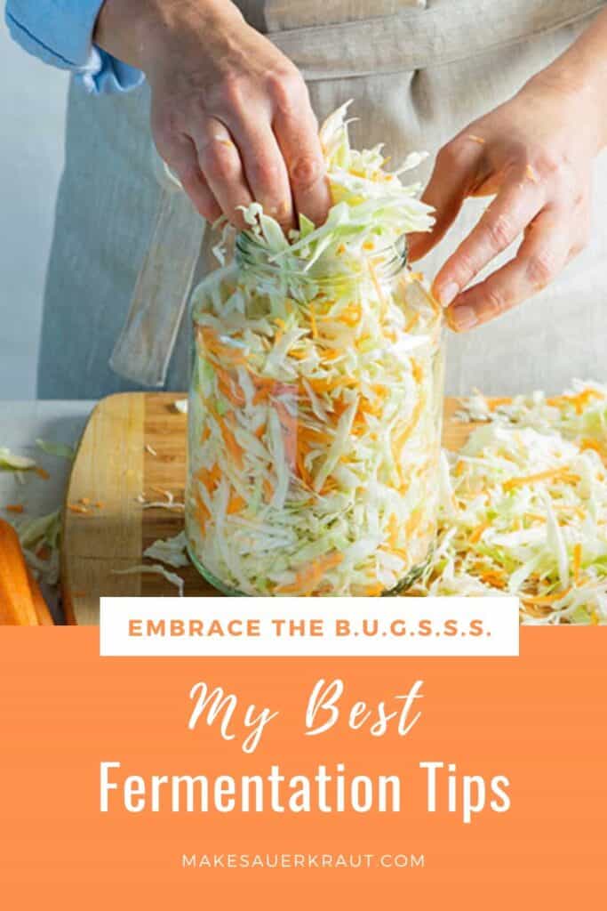 Woman packing a jar with sliced cabbage and grated carrot mixture for making sauerkraut.