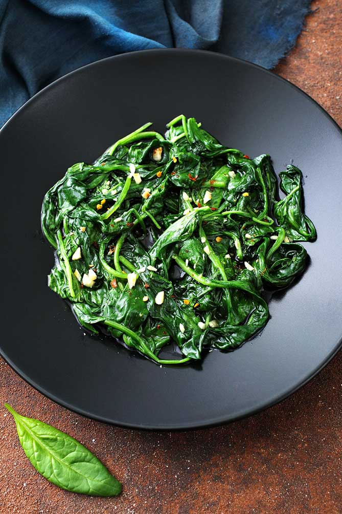 Sauteed green vegetables in a black plate. | MakeSauerkraut.com
