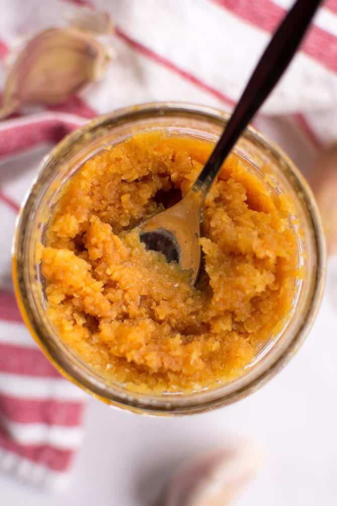 Top view of a spoon in a jar of fermented garlic paste. | MakeSauerkraut.com