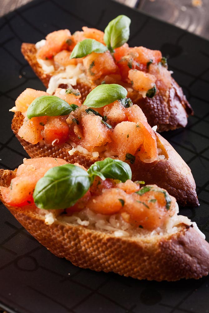 Fermented garlic paste used to make three bruschetta garnished with basil leaves. | MakeSauerkraut.com