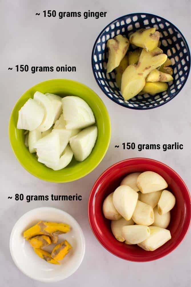 Top view of ingredients for fermented garlic paste in bowls such as turmeric, garlic, onions, and ginger. | MakeSauerkraut.com
