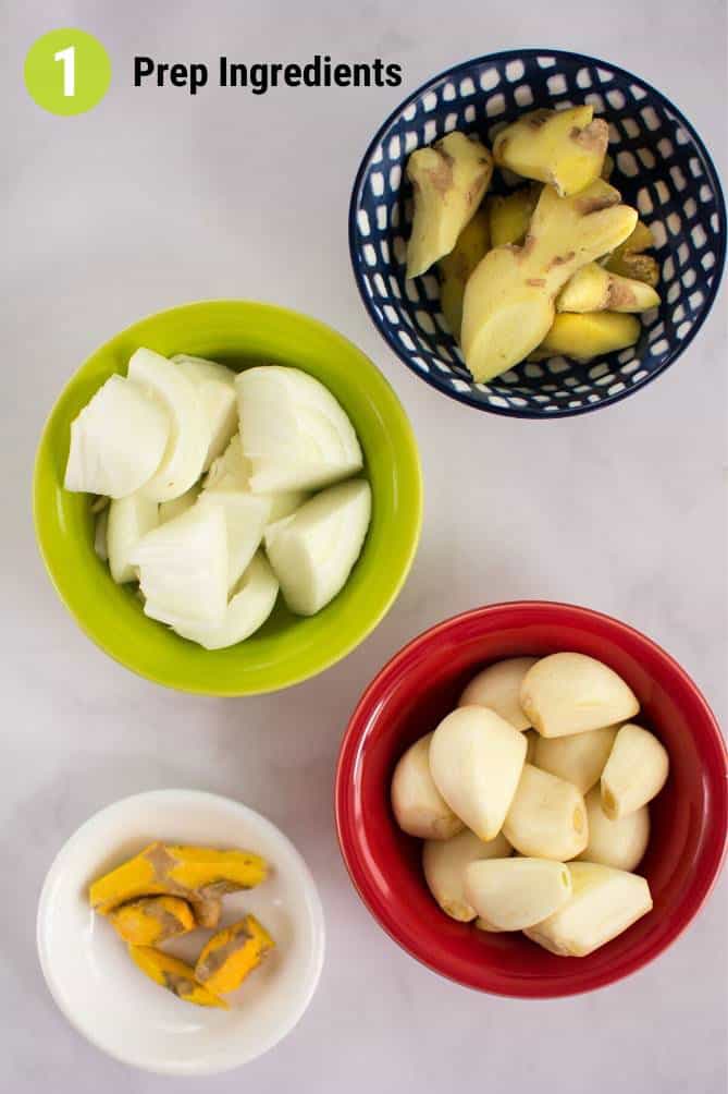 Top view of ingredients for fermented garlic paste in bowls such as turmeric, garlic, onions, and ginger. | MakeSauerkraut.com