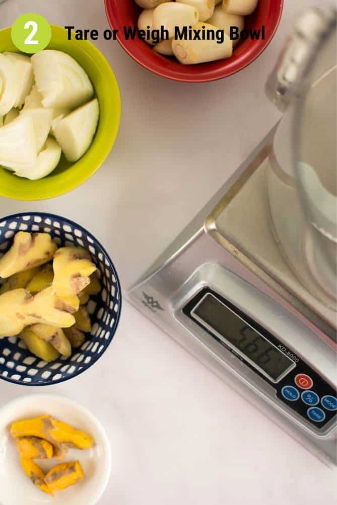 Top view of ingredients for fermented garlic paste in bowls such as turmeric, garlic, onions, and ginger next to a MyWeigh KD-8000 scale. | MakeSauerkraut.com