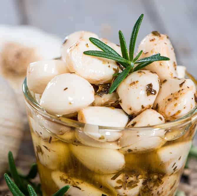 A jar of lacto-fermented garlic cloves seasoned with rosemary. | Makesauerkraut.com
