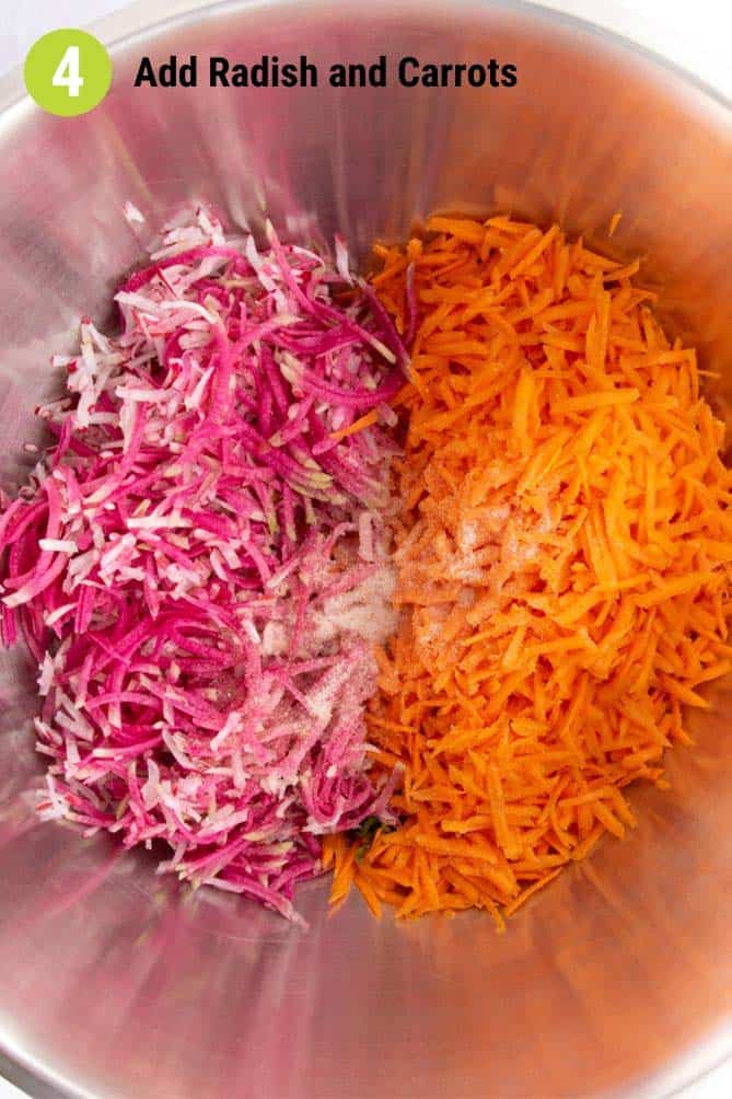 Grated carrots and radish in a metal bowl with salt. | MakeSauerkraut.com