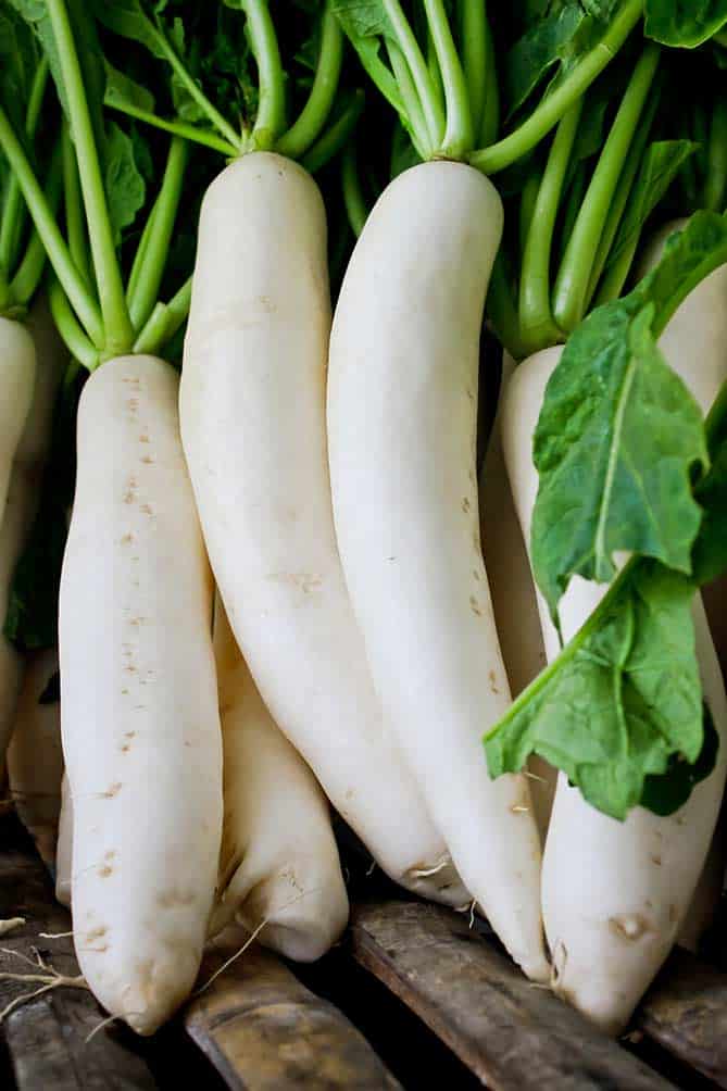 Bunch of daikon radish on wood slats. | MakeSauerkraut.com