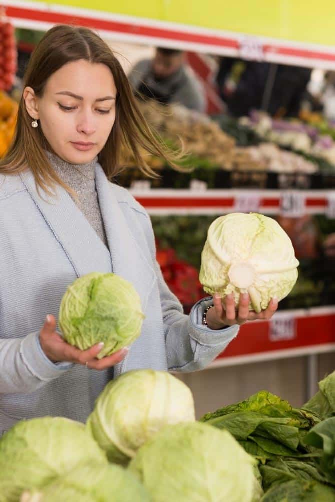 Woman in store holding a head a cabbage in each hand. | MakeSauerkraut.com