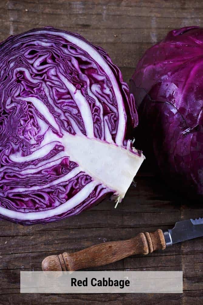 Cut half of red cabbage on a cutting board with a knife. | MakeSauerkraut.com