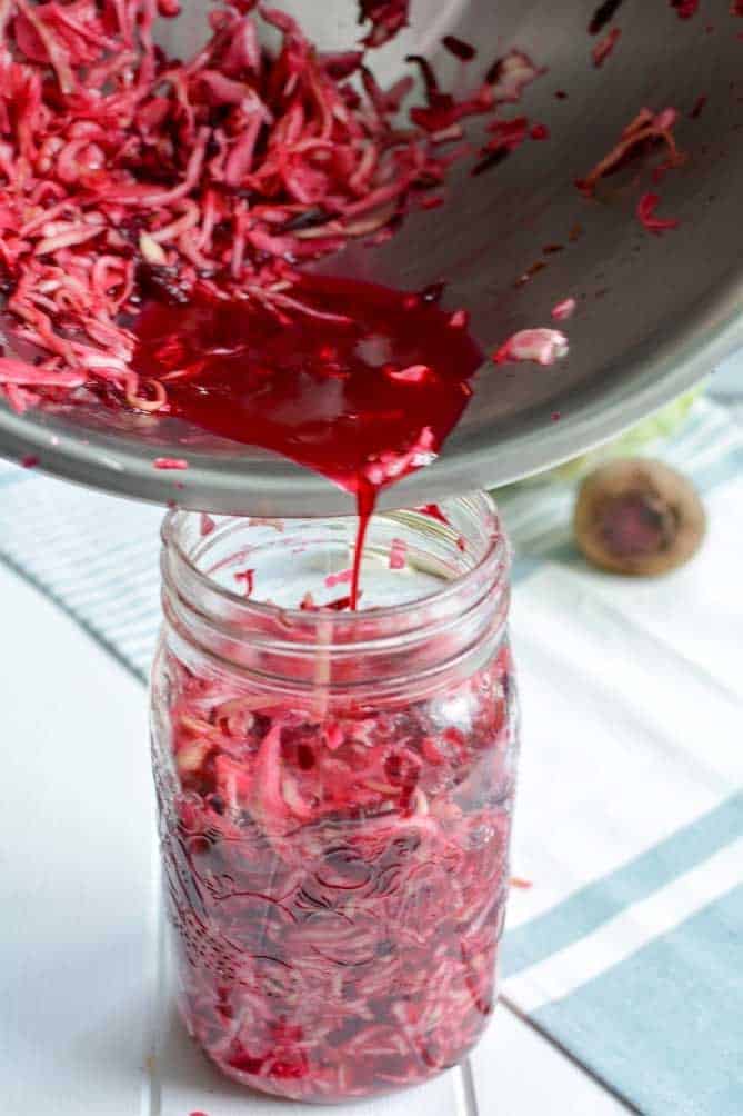 Pouring brine from bowl into jar of sauerkraut. | MakeSauerkraut.com