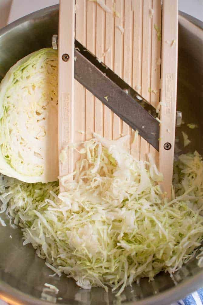 Bowl with sliced cabbage and mandoline. | MakeSauerkraut.com