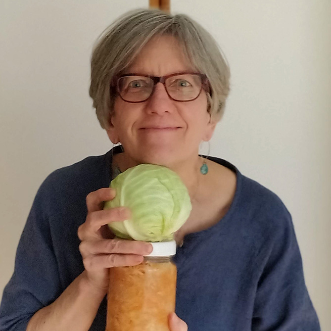 Holly Howe with a cabbage and a jar of sauerkraut. | MakeSauerkraut.com