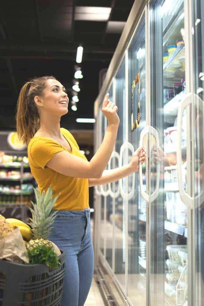 Woman looking in fridge section of grocery store. | MakeSauerkraut.com