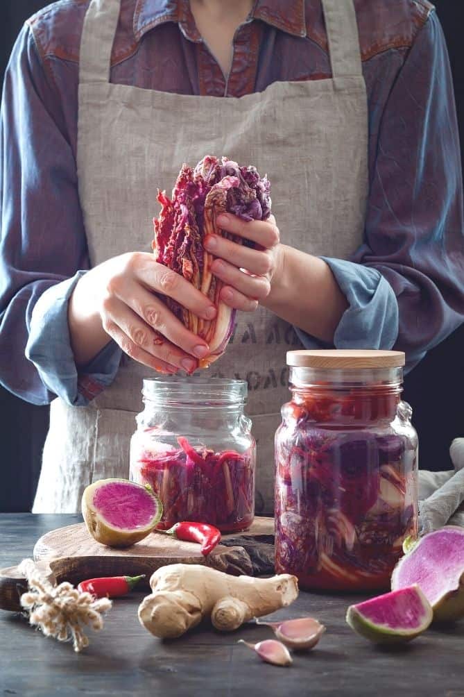 Woman in apron packing cabbage into jar. | MakeSauerkraut.com