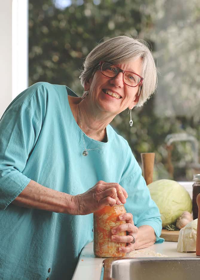 Holly Howe in her kitchen capping a jar of sauerkraut. | MakeSauerkraut.com