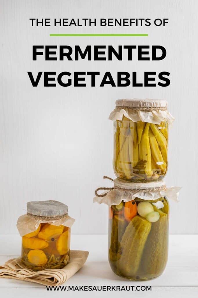 Stack of fermented vegetables jars with text overlay The Health Benefits of Fermented Vegetables. | MakeSauerkraut.com.